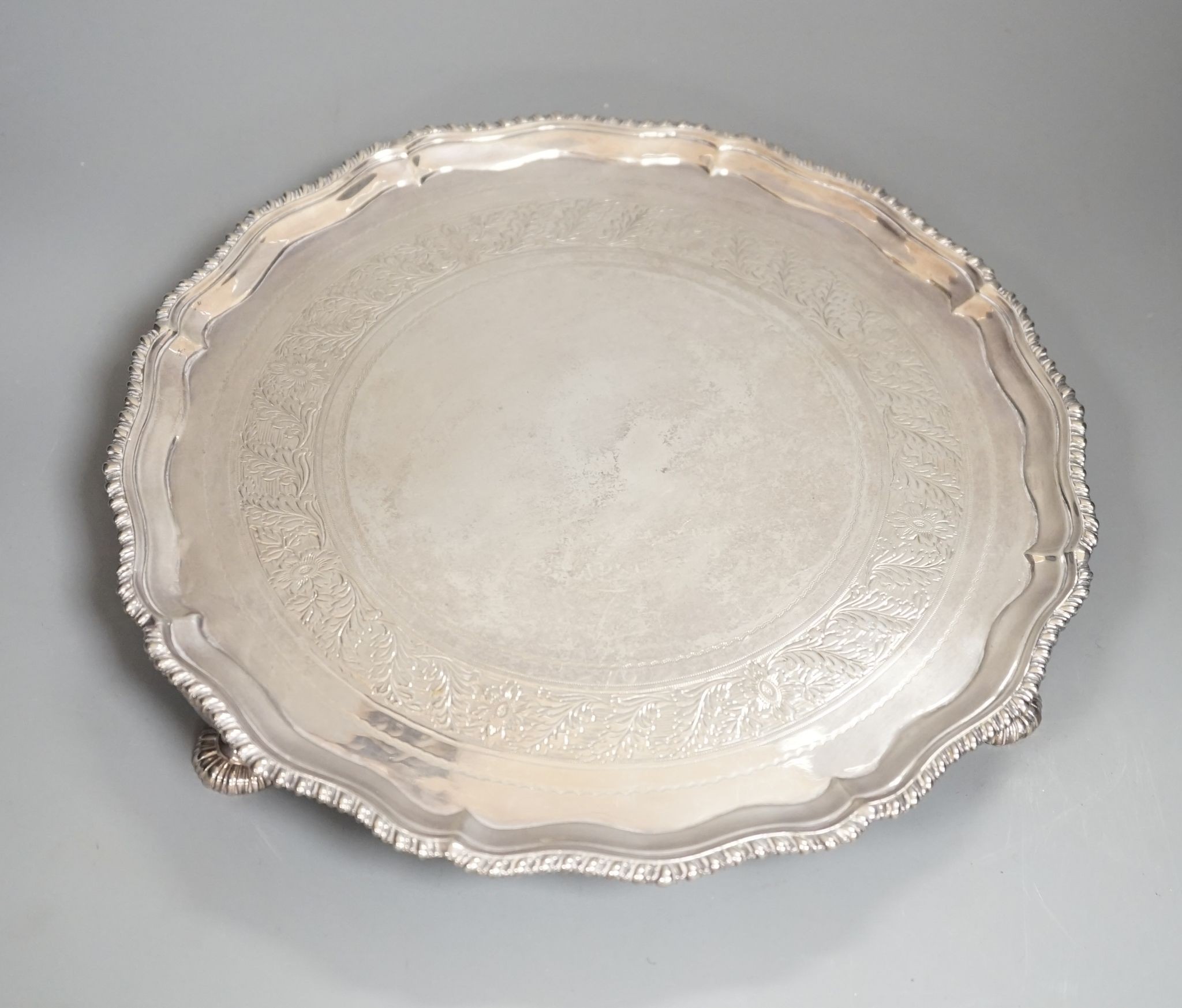 A George III silver salver, with gadrooned border, on three shell feet, Ebenezer Coker, London, 1773, 28.1cm, (repairs), 20.5oz.